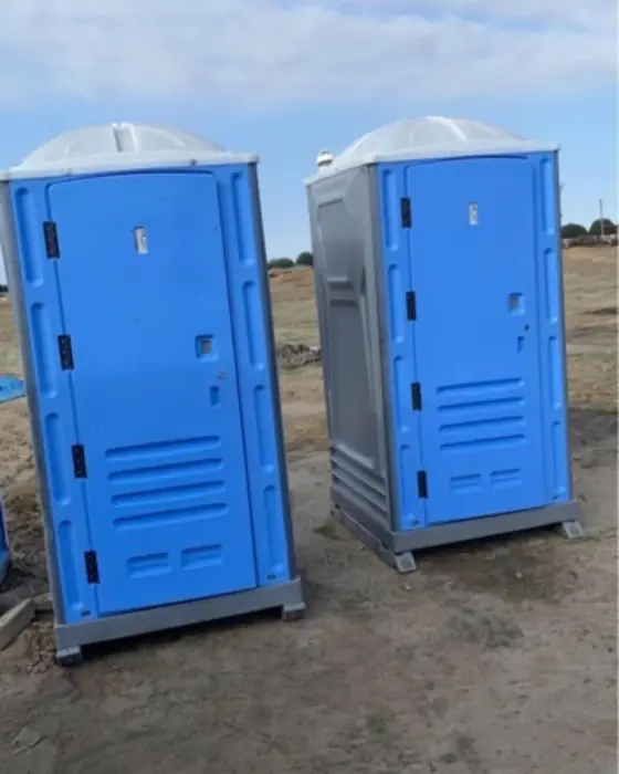 Blue and gray porta potties on an open job site