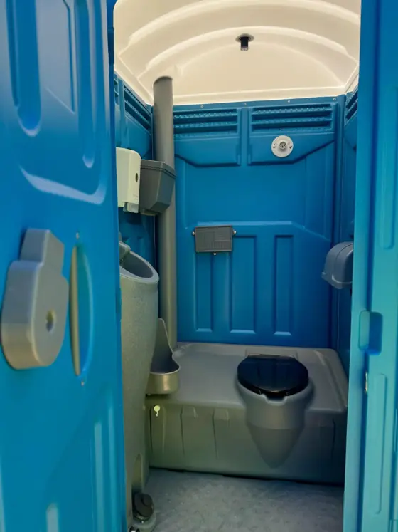 Clean blue porta potty interior with seat and urinal