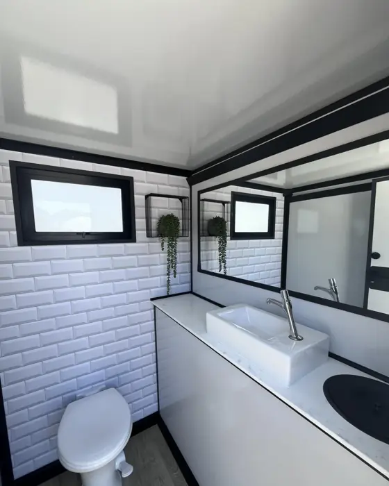 Restroom trailer stall with white tile walls, vessel sink and mirror