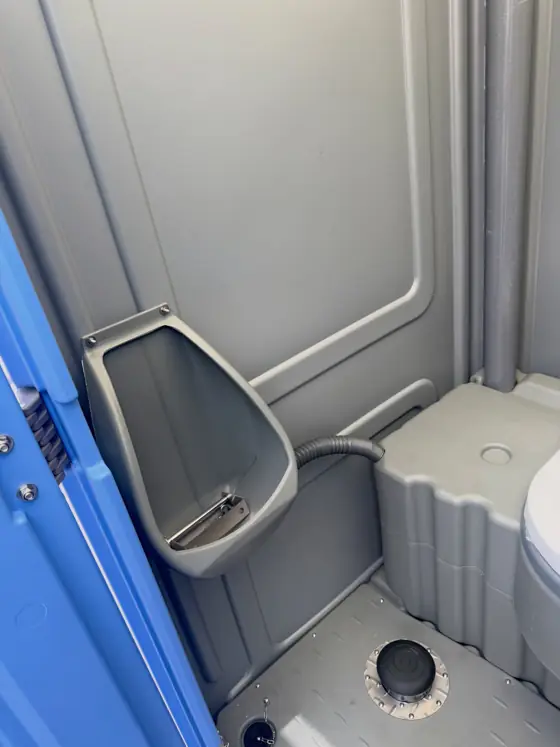 Urinal mounted on the wall inside a standard porta potty